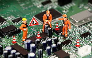 Miniature Workers Repairing Circuit Board with Traffic Cones and Warning Sign HD wallpaper