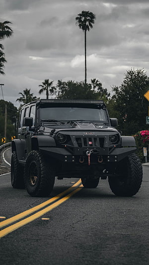 Matte Black Modified Jeep Wrangler with Off-Road Bumper and LED Light Bar on Road HD phone wallpaper