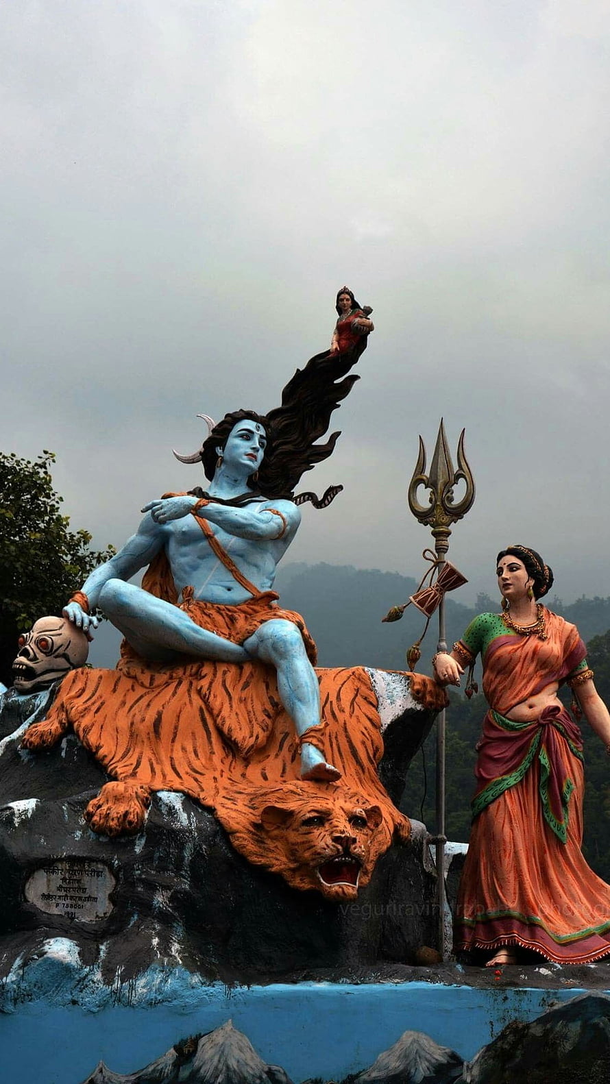 Majestic statue of Lord Shiva sitting on a tiger skin with Parvati holding a trident and a skull HD phone wallpaper