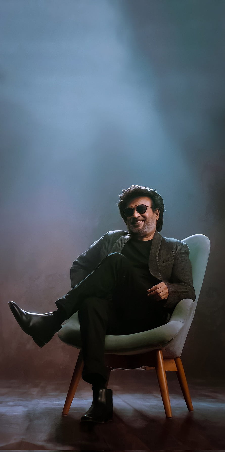Rajinikanth sitting in a chair wearing sunglasses and a dark suit with dramatic lighting HD phone wallpaper