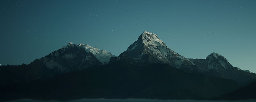 Snow-Capped Mountain Peaks Under a Starry Night Sky HD wallpaper