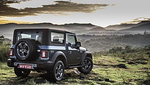 Mahindra Thar SUV parked on grassy hillside with mountain sunset background HD wallpaper