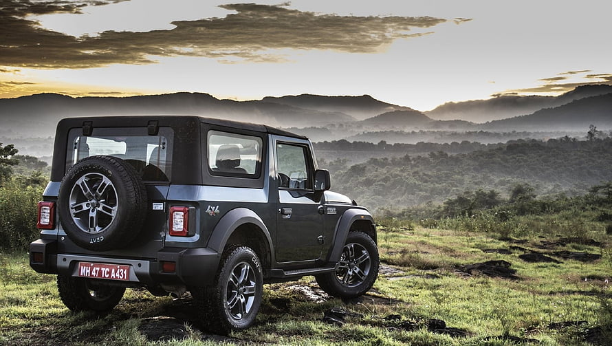 Mahindra Thar SUV parked on grassy hillside with mountain sunset background HD wallpaper