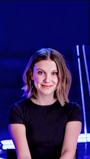 Millie Bobby Brown Portrait in Black Top with Blue Neon Lighting HD phone wallpaper
