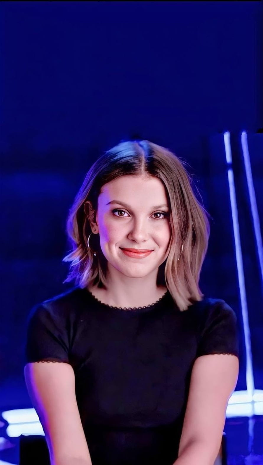 Millie Bobby Brown Portrait in Black Top with Blue Neon Lighting HD phone wallpaper