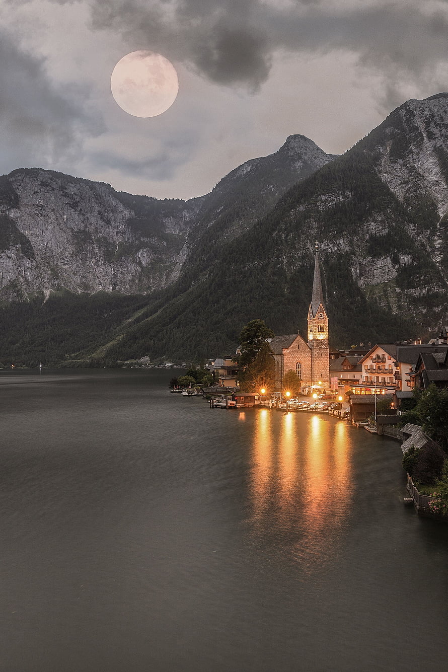 Hallstatt Village at Dusk with Full Moon and Church Spire Reflected in Lake HD phone wallpaper