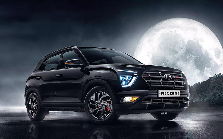 Black Hyundai Venue SUV with red accents parked on wet road under giant full moon HD wallpaper
