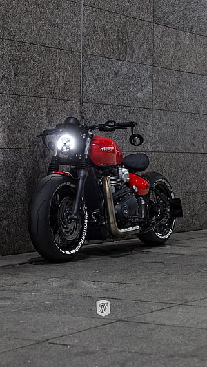 Red Triumph Bobber Motorcycle Parked Against Grey Stone Wall HD phone wallpaper