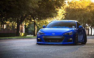 Blue Subaru BRZ sports coupe parked on a tree-lined street at golden hour HD wallpaper