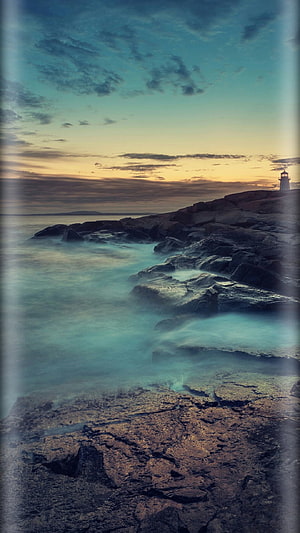 Long Exposure Coastal Scene with Lighthouse at Sunset Over Rocky Shore HD phone wallpaper
