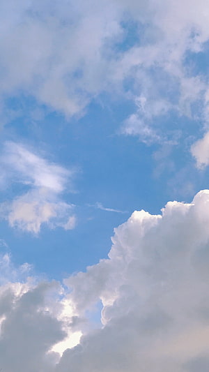 Serene Blue Sky With Fluffy White Clouds And Sunlight Breaking Through For A Peaceful Nature Background HD phone wallpaper