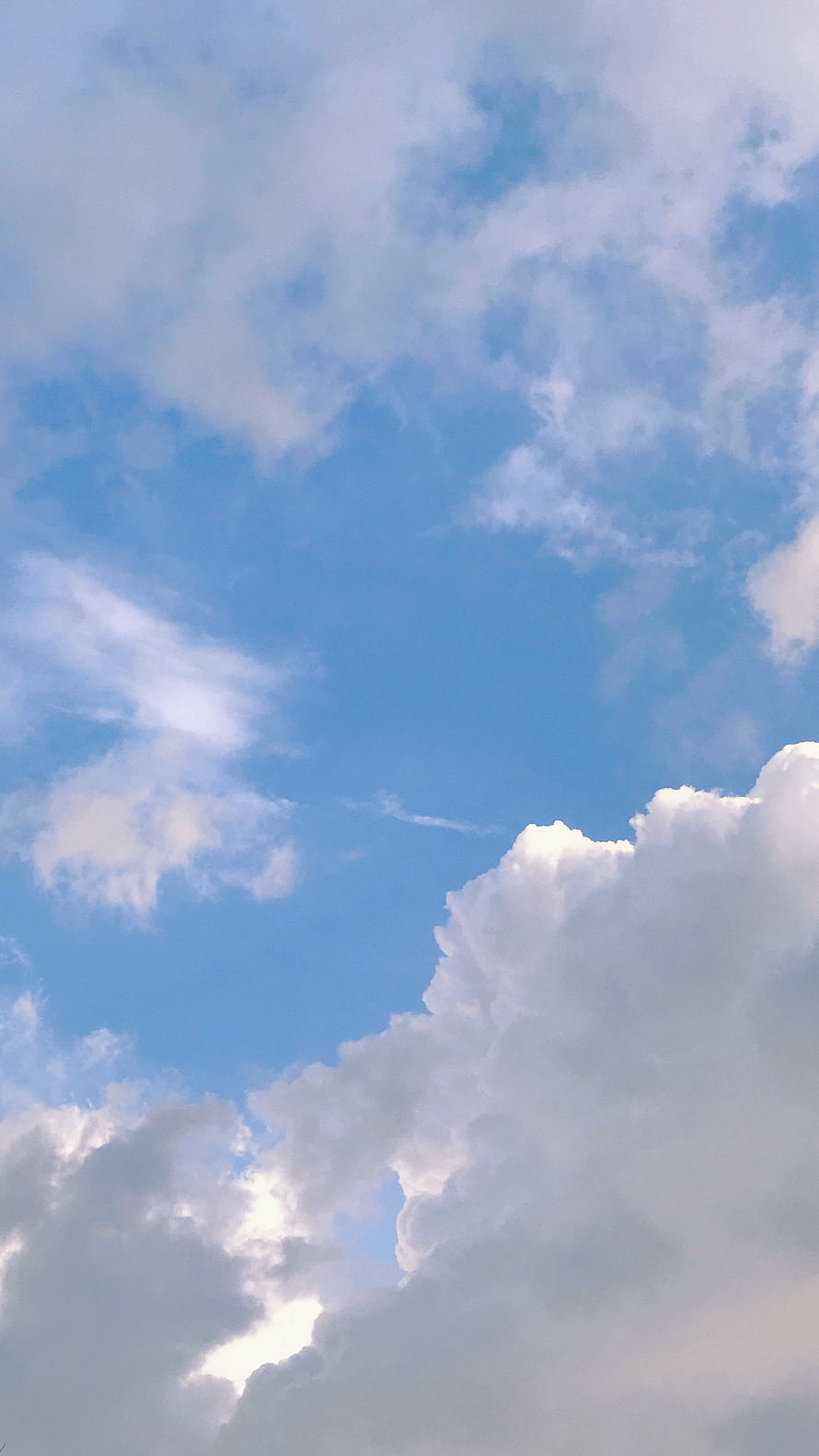 Serene Blue Sky With Fluffy White Clouds And Sunlight Breaking Through For A Peaceful Nature Background HD phone wallpaper
