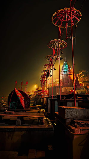 Varanasi Ghat at Night with Illuminated Temple and Decorated Poles HD phone wallpaper