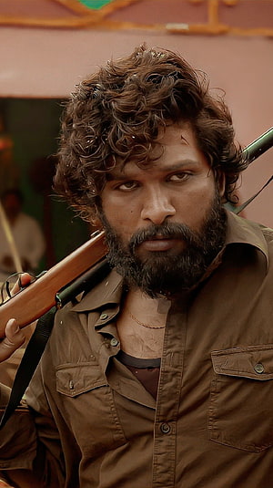 Allu Arjun as Pushpa in gritty action scene with rifle over shoulder HD phone wallpaper