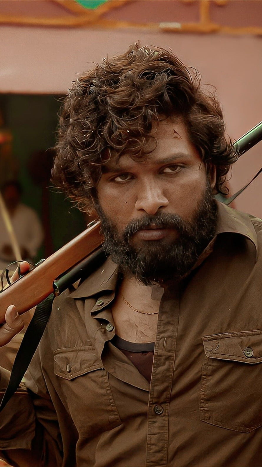 Allu Arjun as Pushpa in gritty action scene with rifle over shoulder HD phone wallpaper