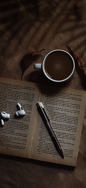 Cozy Reading Scene with Open Book, Coffee, and Wireless Earbuds HD phone wallpaper