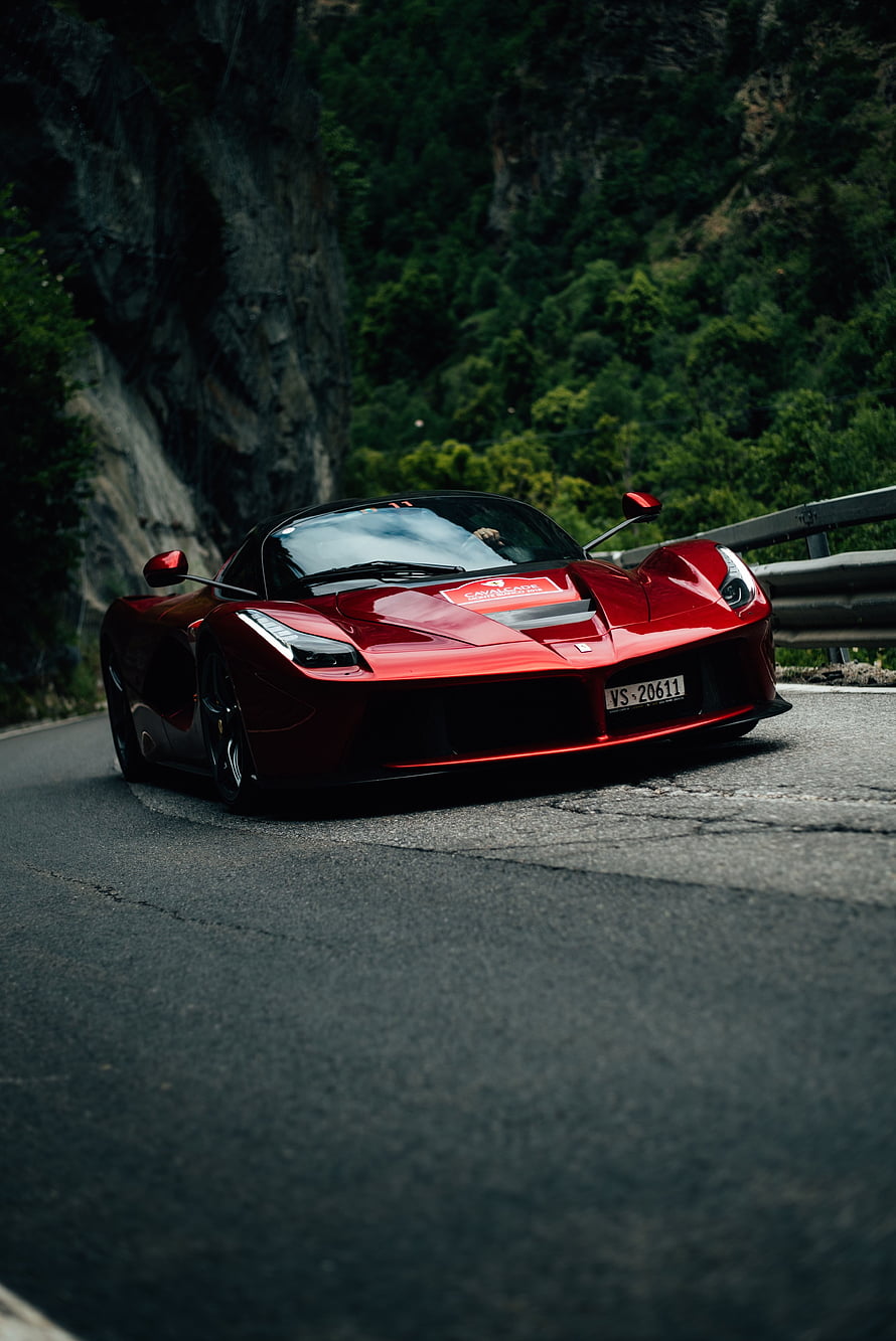 Red Ferrari LaFerrari driving on a winding mountain road with lush green forest background HD phone wallpaper
