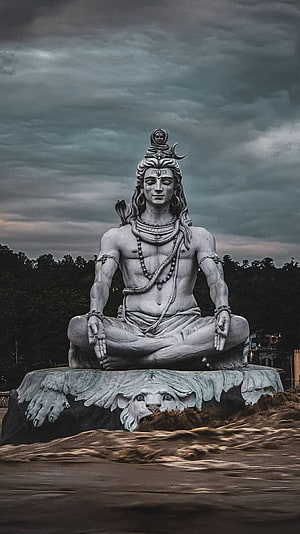Majestic White Statue of Lord Shiva Meditating on a Rock Under Stormy Sky HD phone wallpaper