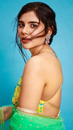 Sai Pallavi in a vibrant green saree with yellow blouse, posing against a blue background HD phone wallpaper