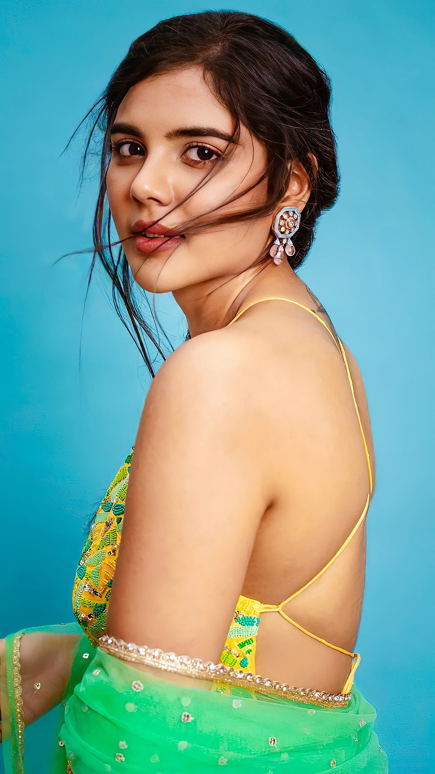 Sai Pallavi in a vibrant green saree with yellow blouse, posing against a blue background HD phone wallpaper