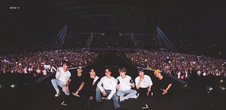 BTS Members Sitting On Stage At A Massive Stadium Concert With A Huge Crowd HD wallpaper