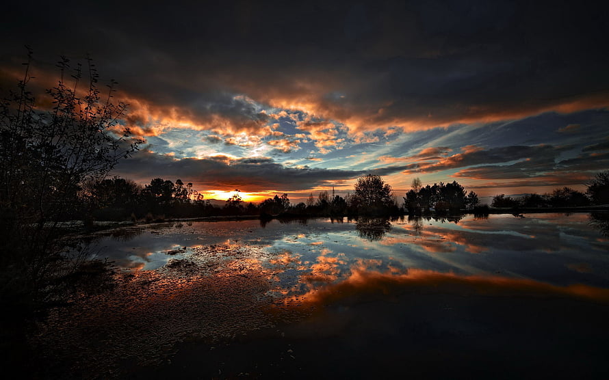 Dramatic sunset over a calm lake with vivid orange and blue cloud reflections HD wallpaper